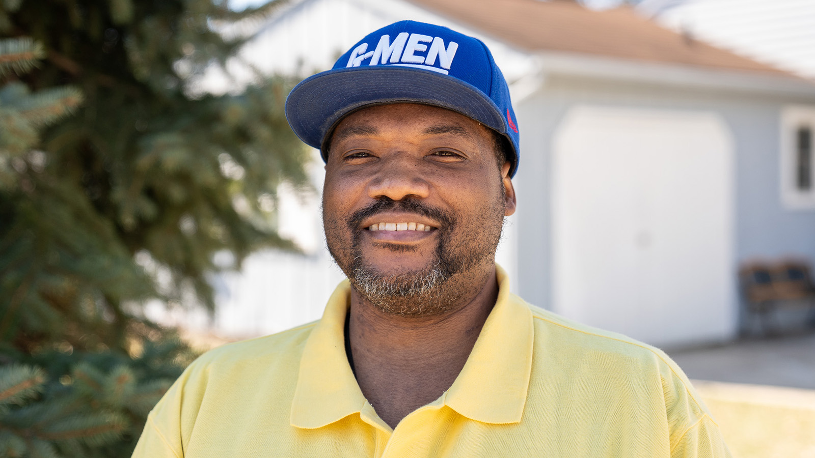 Smiling male stands outside of his home