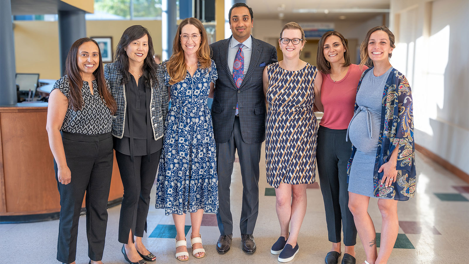Group of doctors, nurses, radiation oncologists, and a young breast cancer survivor in lobby at the Penn Medicine | Virtua Health Proton Therapy Center