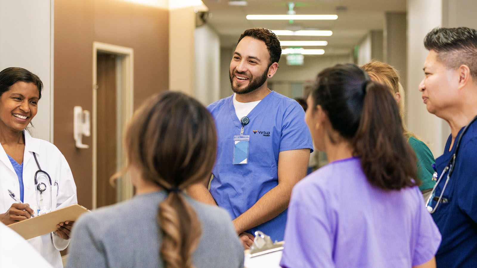 Group of doctors and nurses standing in a circle in a hospital, talking and laughing