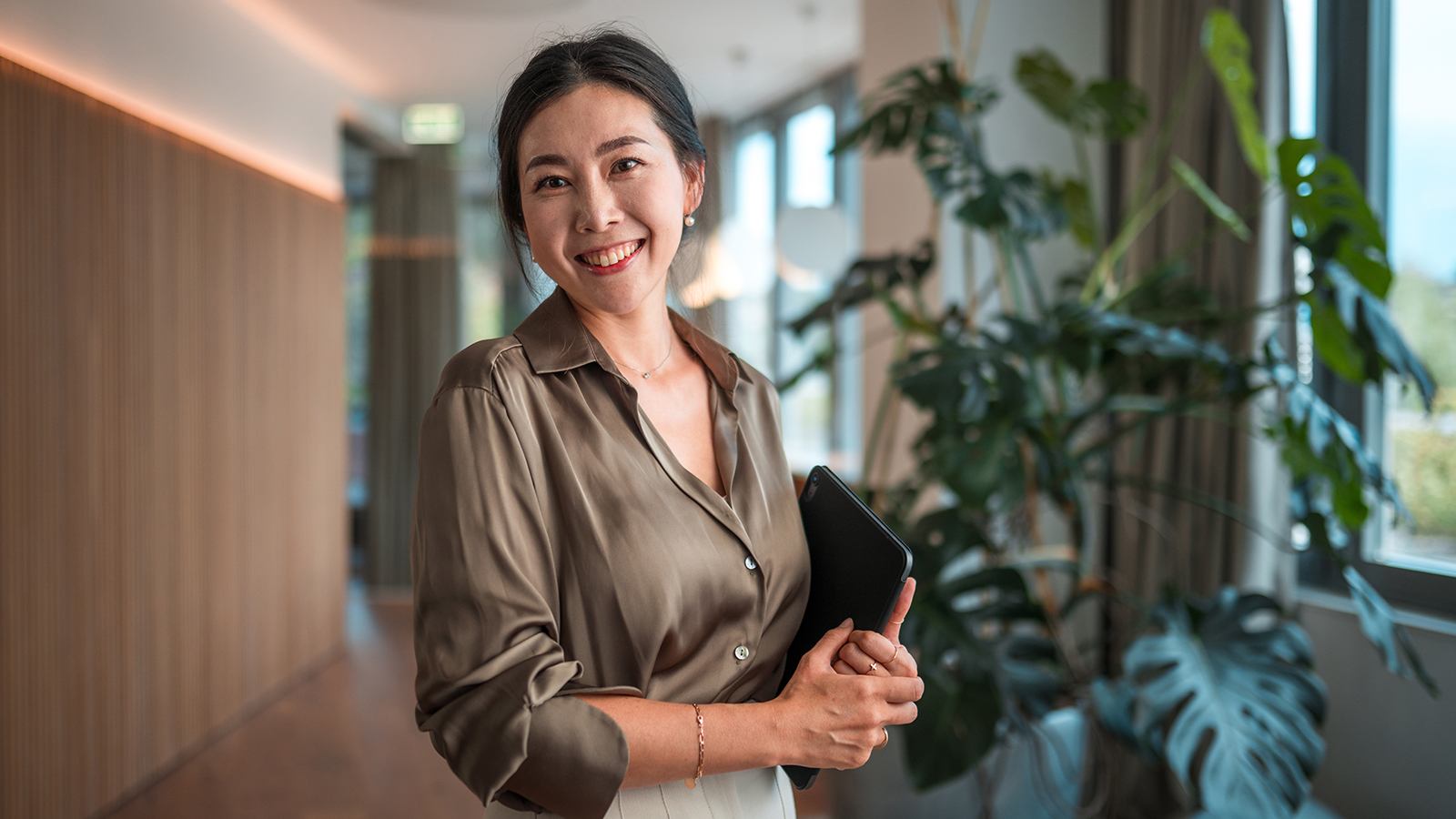 smiling female professional standing in lobby with plants