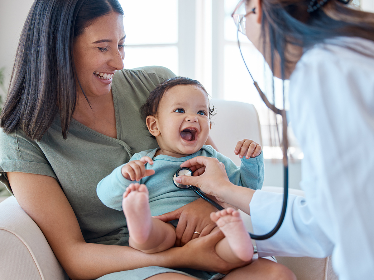 Doctor listening to baby's heart while mom holds baby