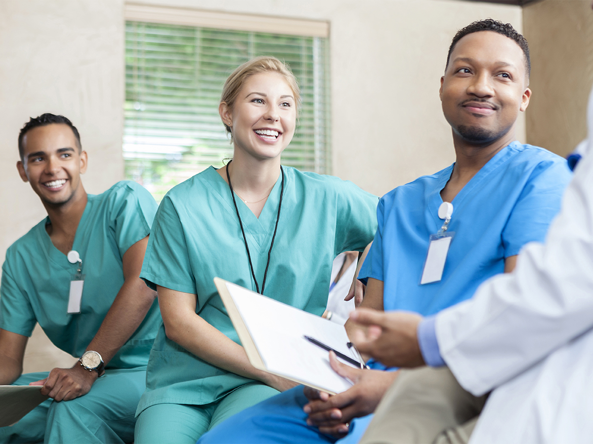 Two male and one female resident doctors smiling and talking