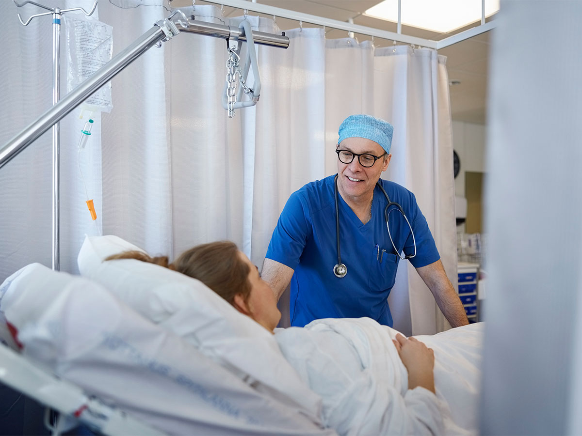 Smiling surgeon at bedside of smiling patient
