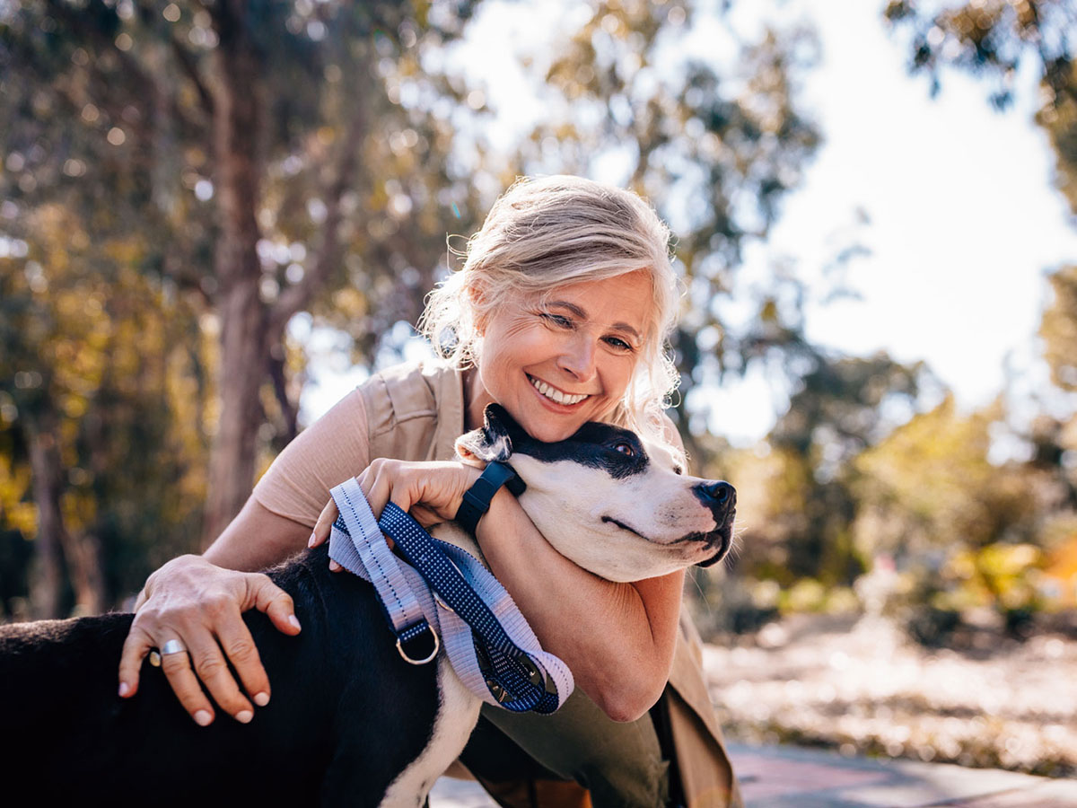 close up on woman smiling hugging her dog at outside the park