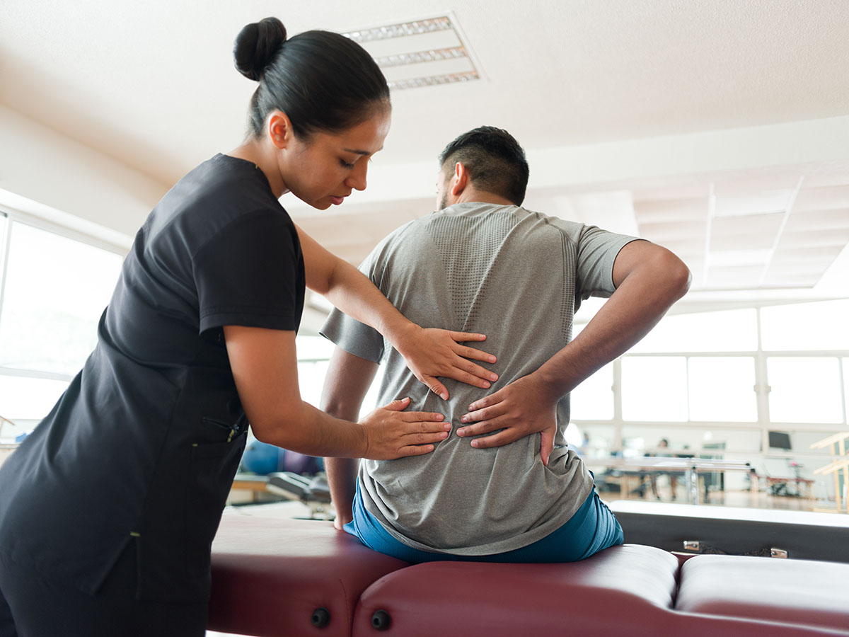 woman assessing a man's spine in a medical setting