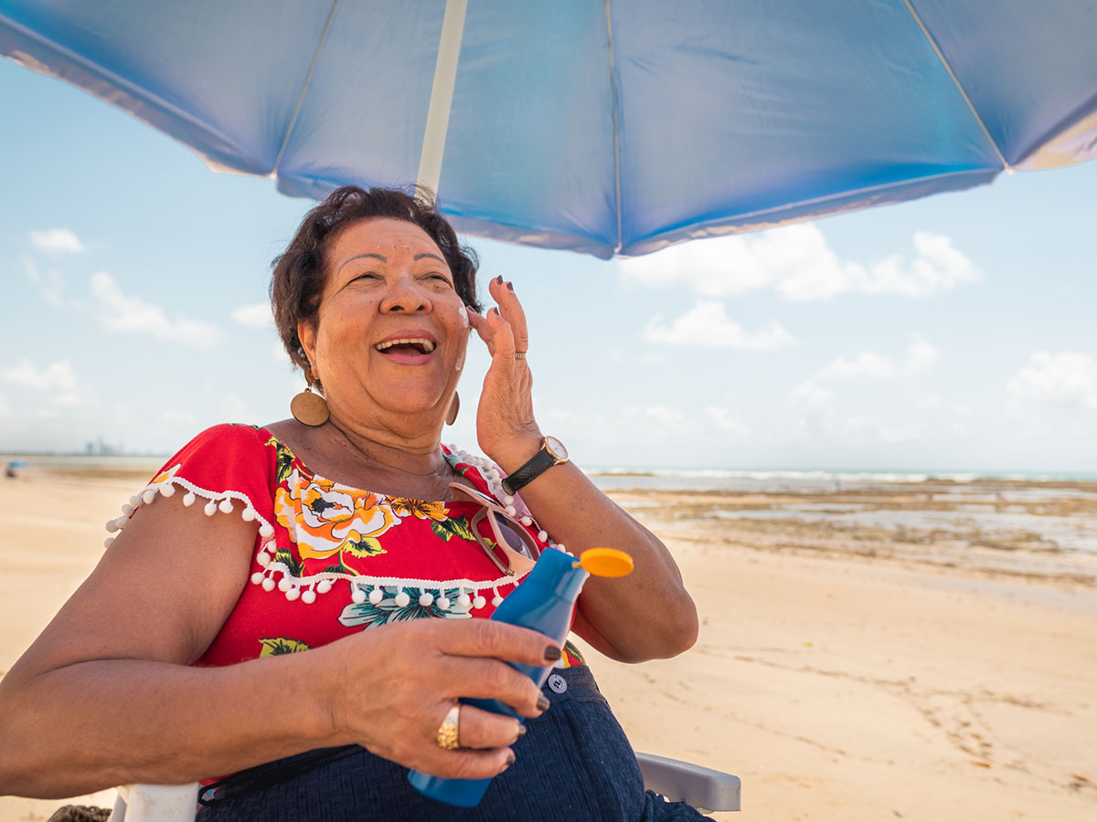 Woman in red shirt at the beach under an umbrella