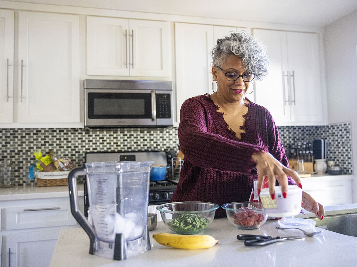 Older woman in the kitchen preparing to make a smoothie