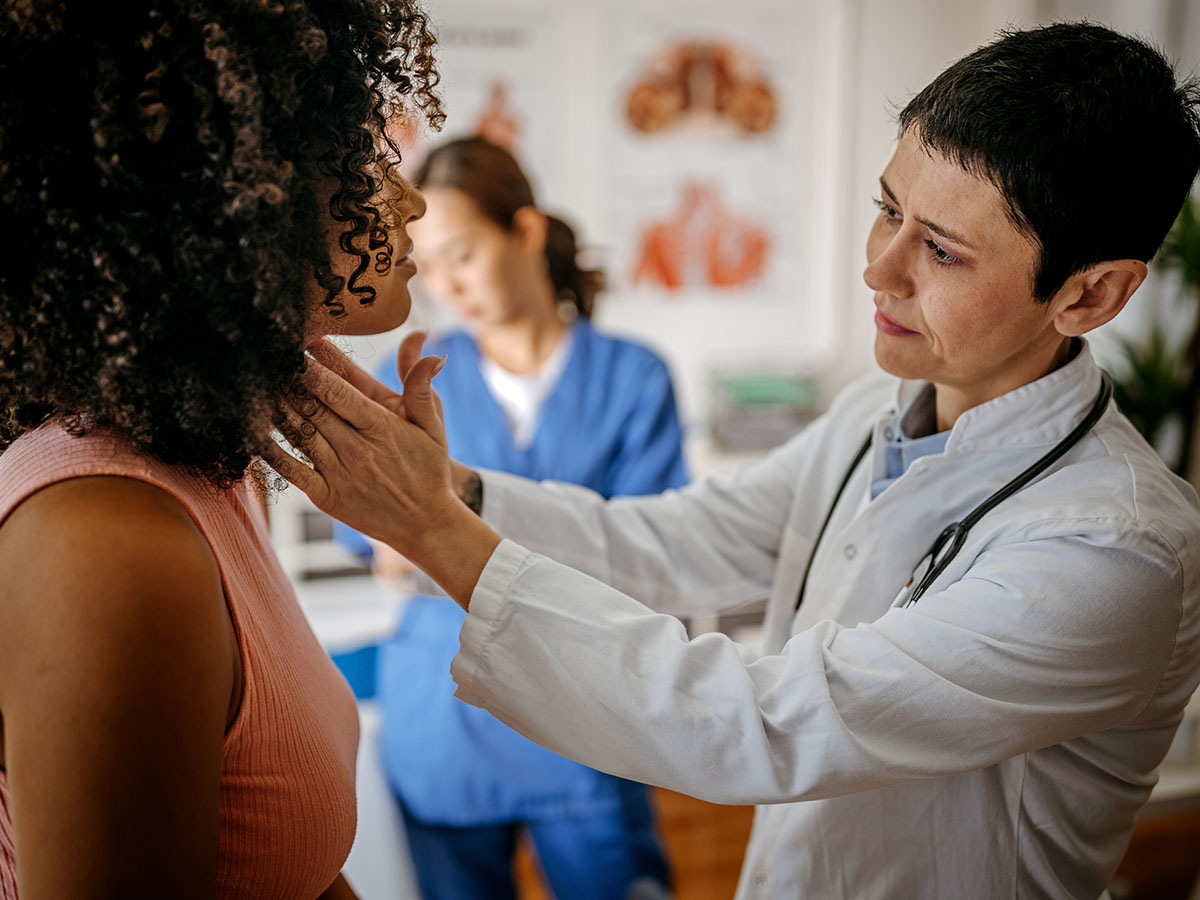 Female doctor touches the neck of a female patient