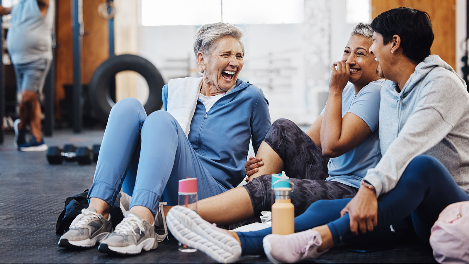 3 female senior citizens laughing while sitting on floor at gym