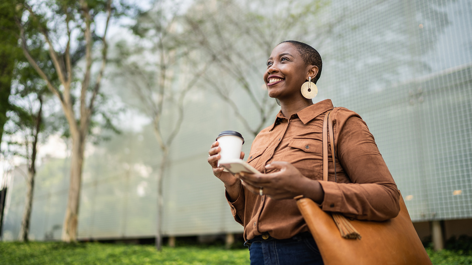 Business woman holding smartphone and looking away outdoors