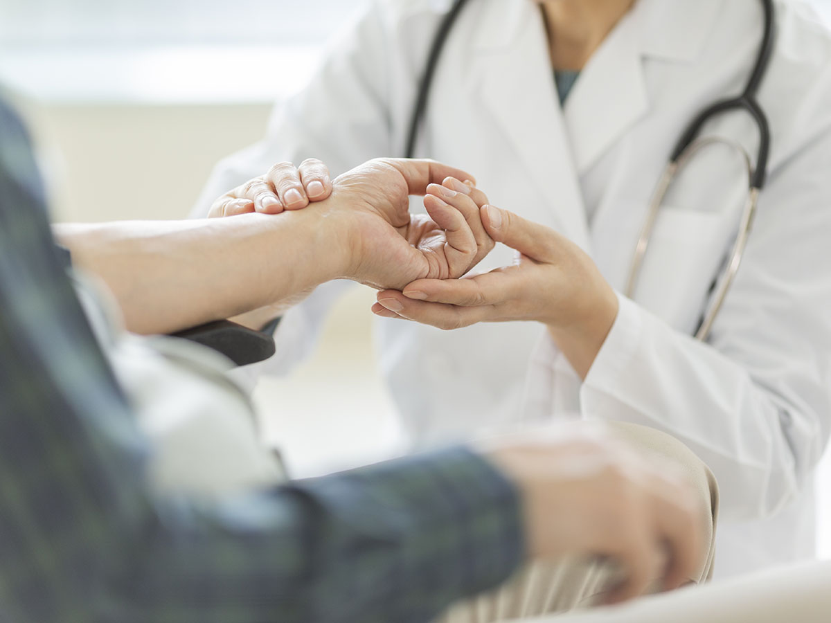 cropped zoomed in image of doctor assessing a patient's wrist.