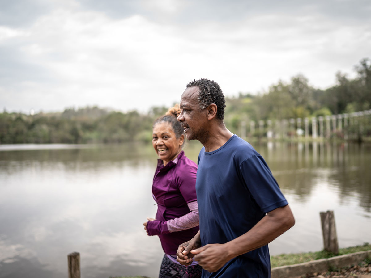 African American couple jog outdoors by a lake