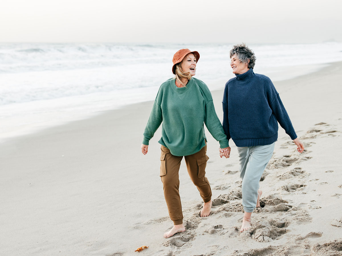 Two older women holding hands on the beach