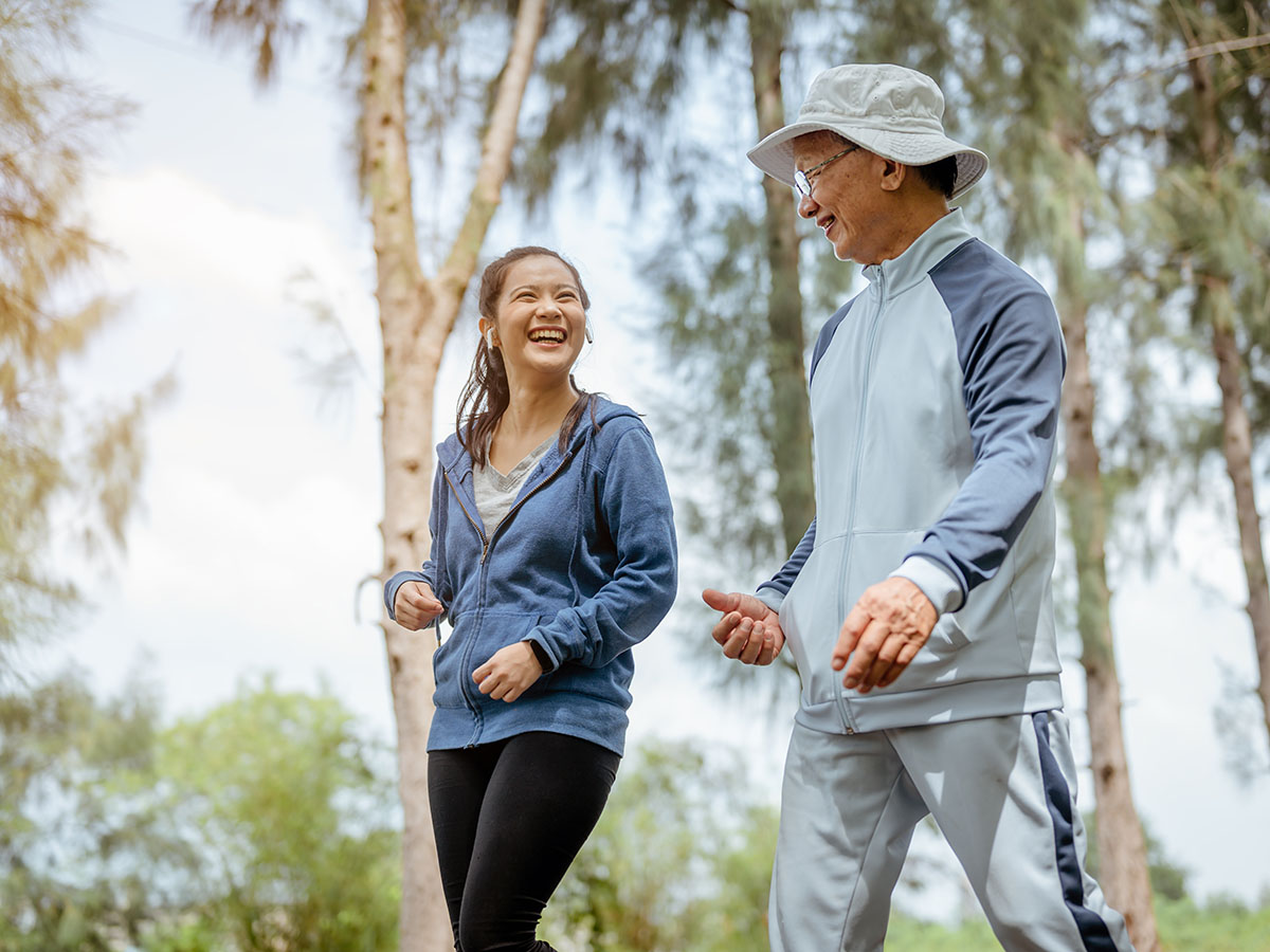 Young woman and grandfather smiling and walking at the park.