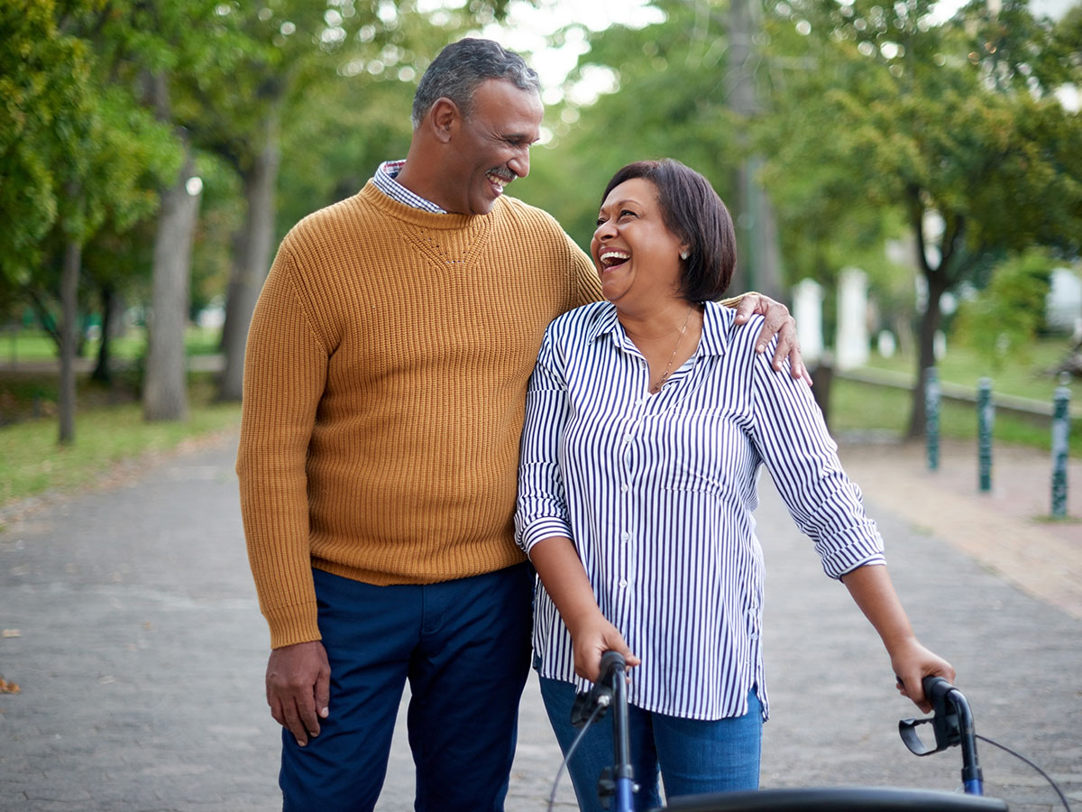 Cropped shot of a happy older woman smiling and walking with a walker.