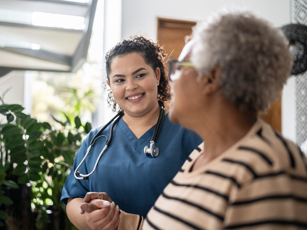 Female nurse holds the hand of a female older patient