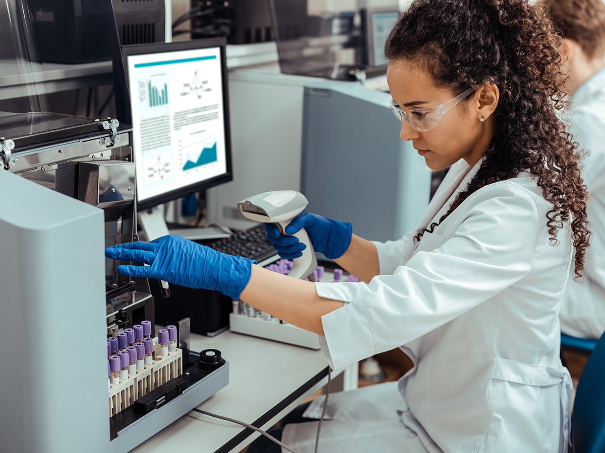 Focused on work. Smart nice woman looking at the test tube while being focused on her work