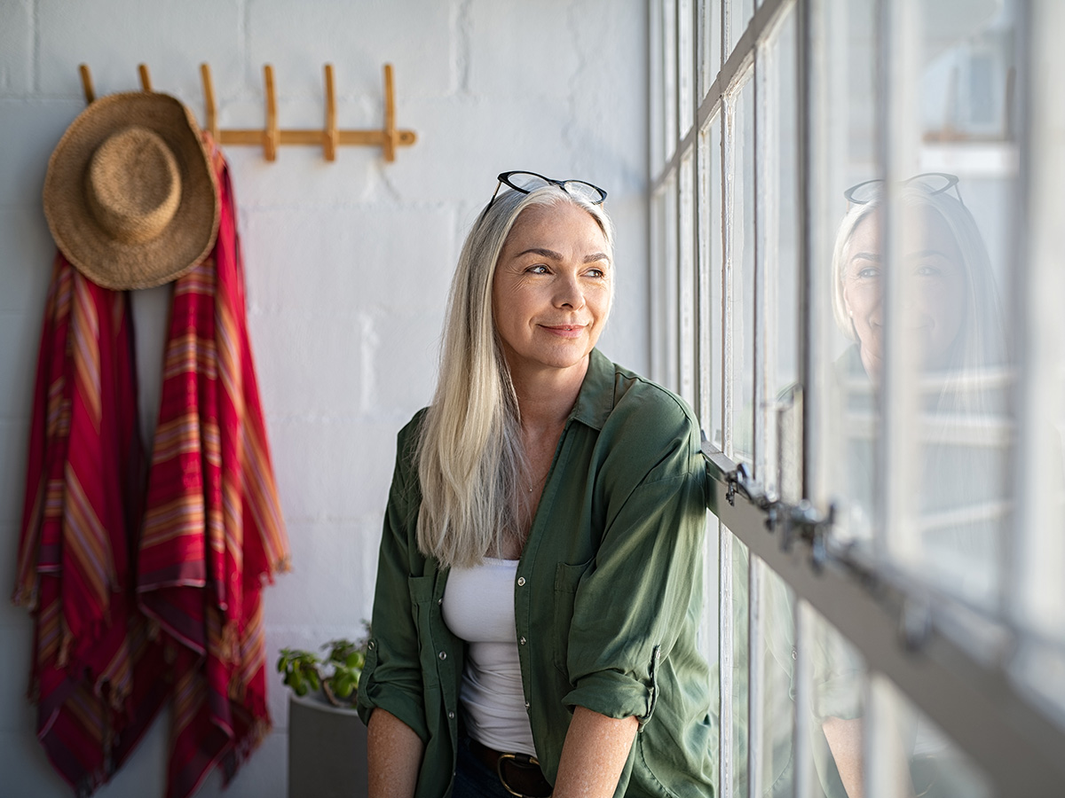 Older woman in a green shirt looks out the window