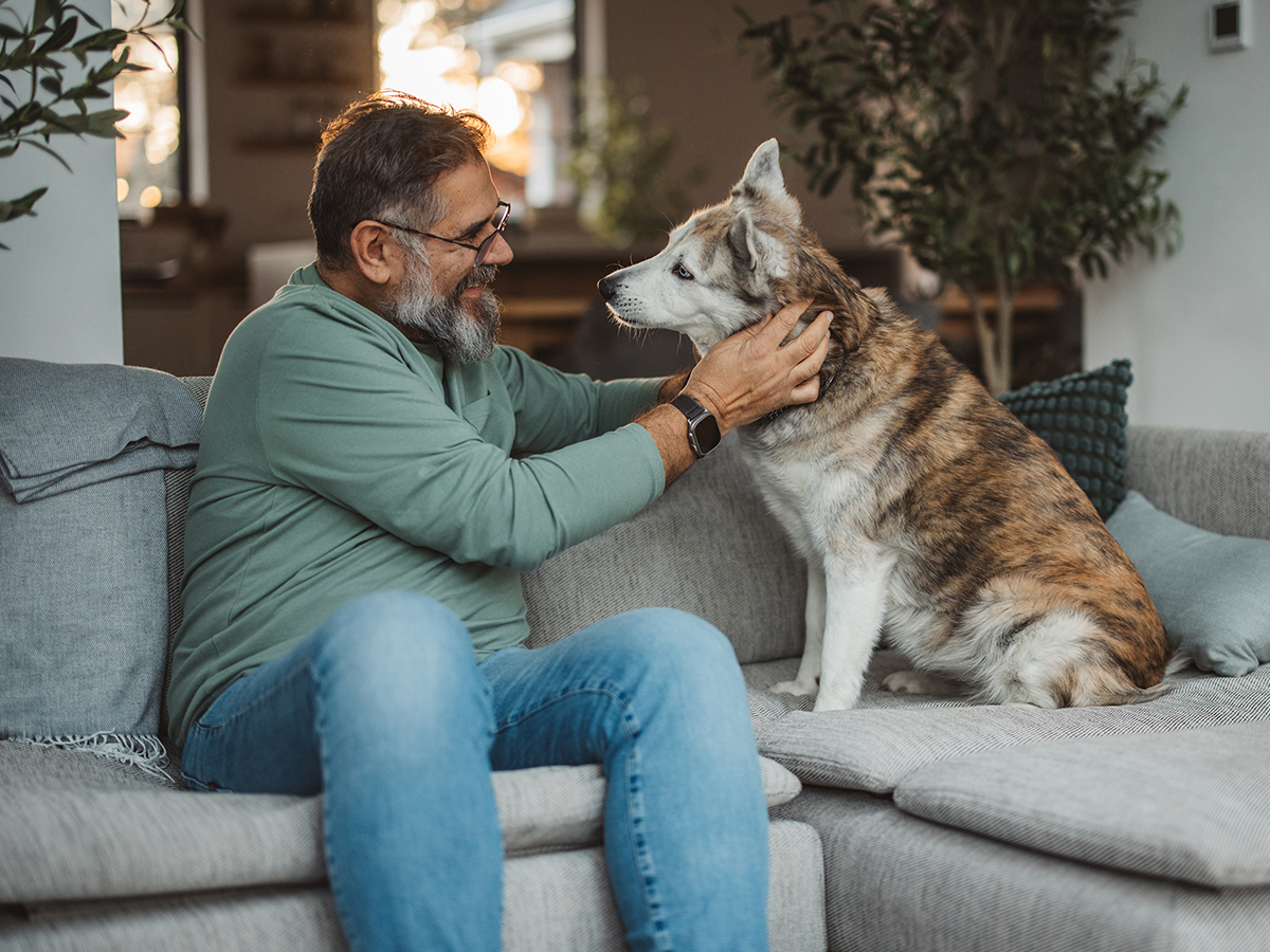 Middle aged male petting dog and smiling