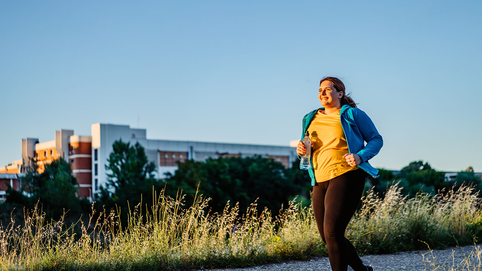 young woman running on a path in front of a building