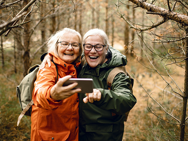 Close up of two female seniors taking a selfie while hiking in the forest