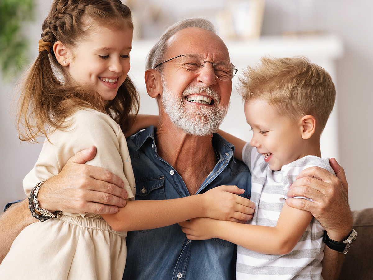 Grandfather holding two young grandchildren and smiling