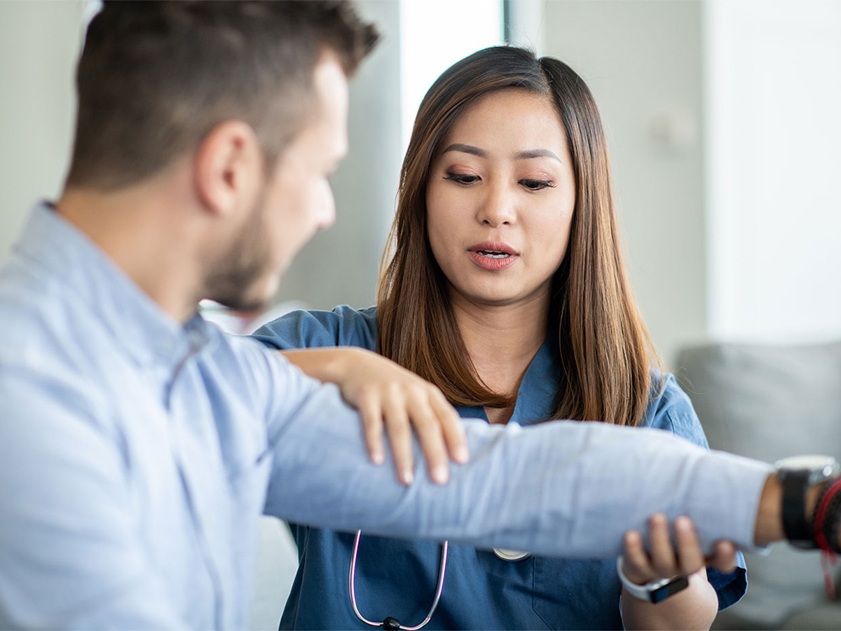 Young female physician bending young male patient's elbow during an exam