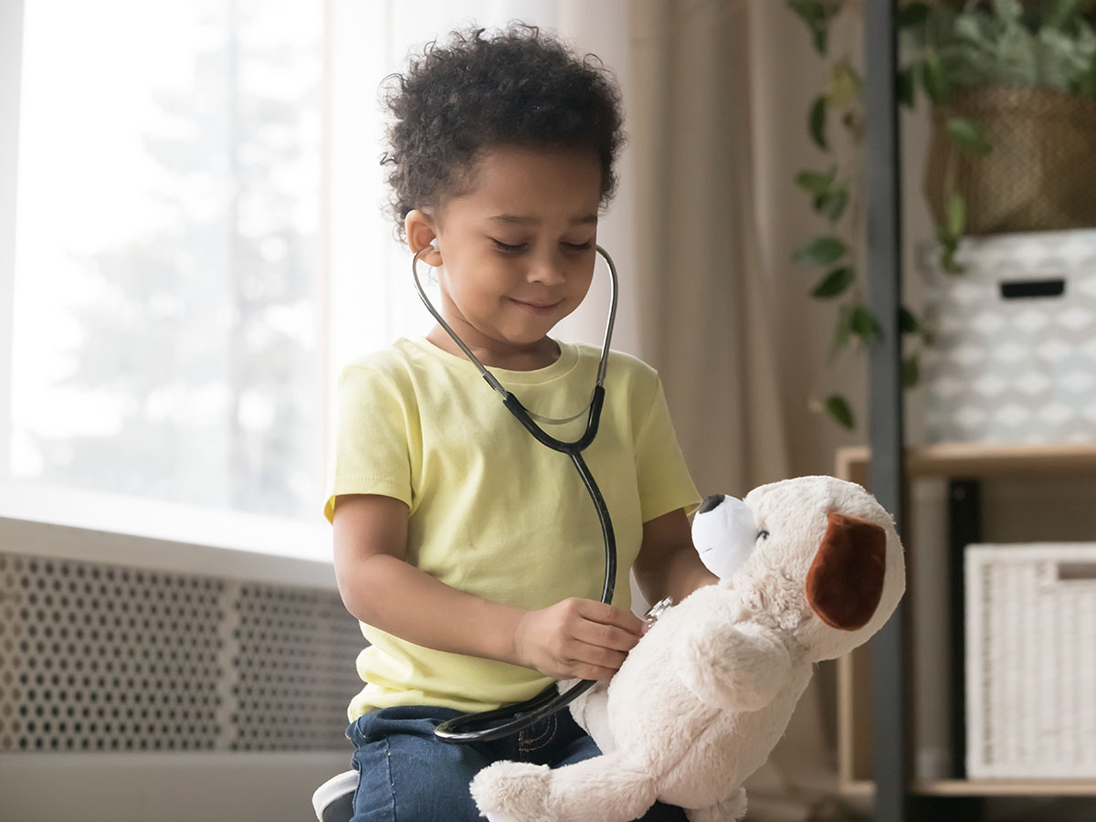Young child with stethoscope and teddy bear.