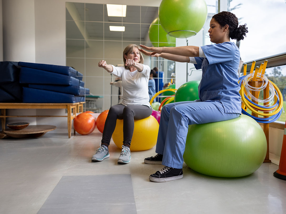 Two women doing physical therapy with gym balls
