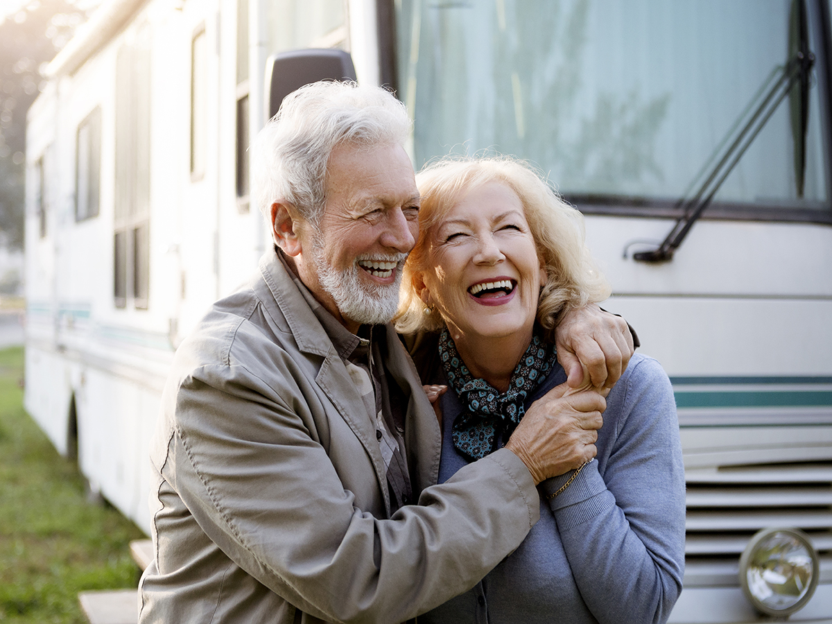 Older man and women laughing outside in front of an RV