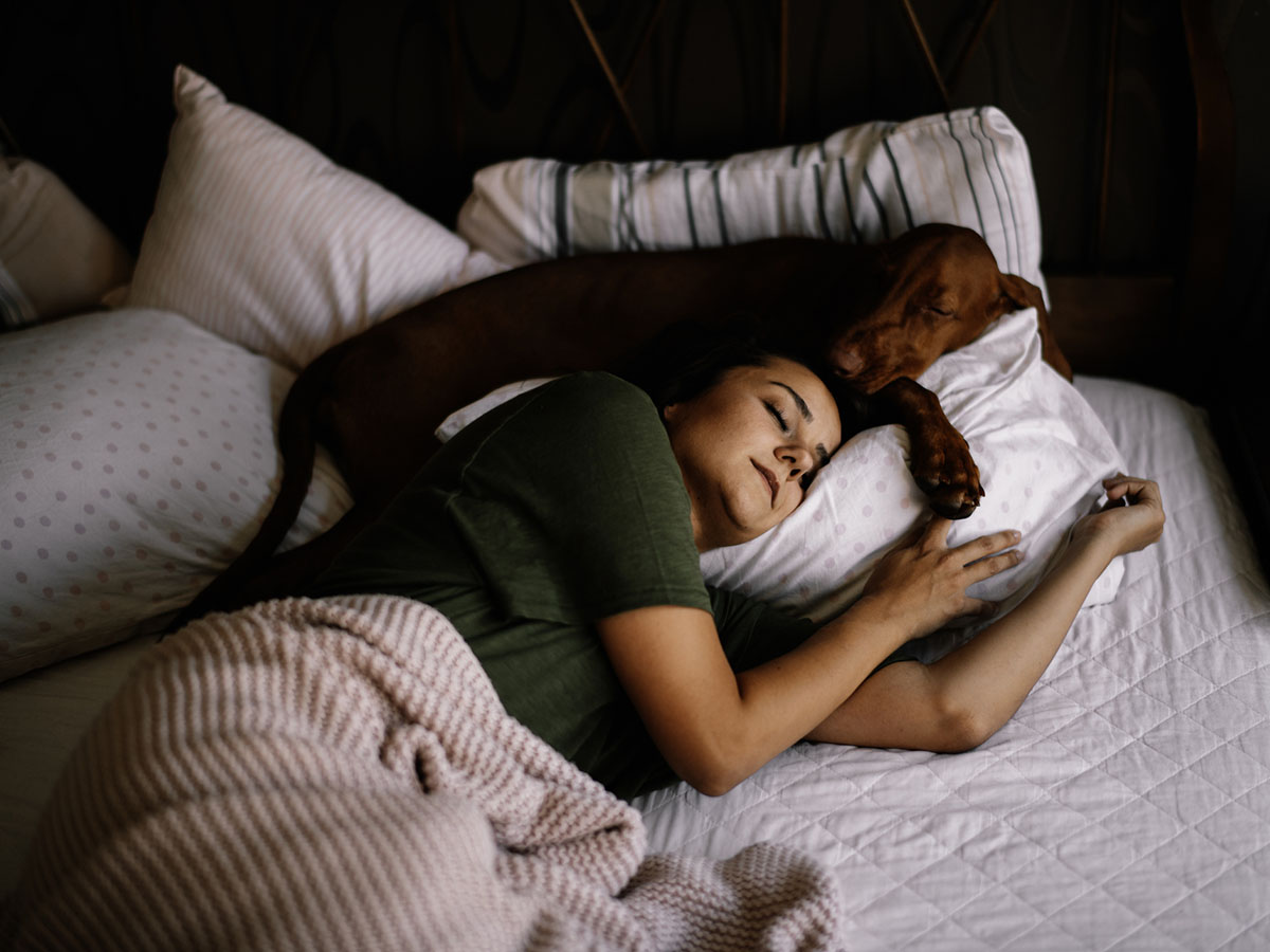 A woman is fast asleep in bed with her dog