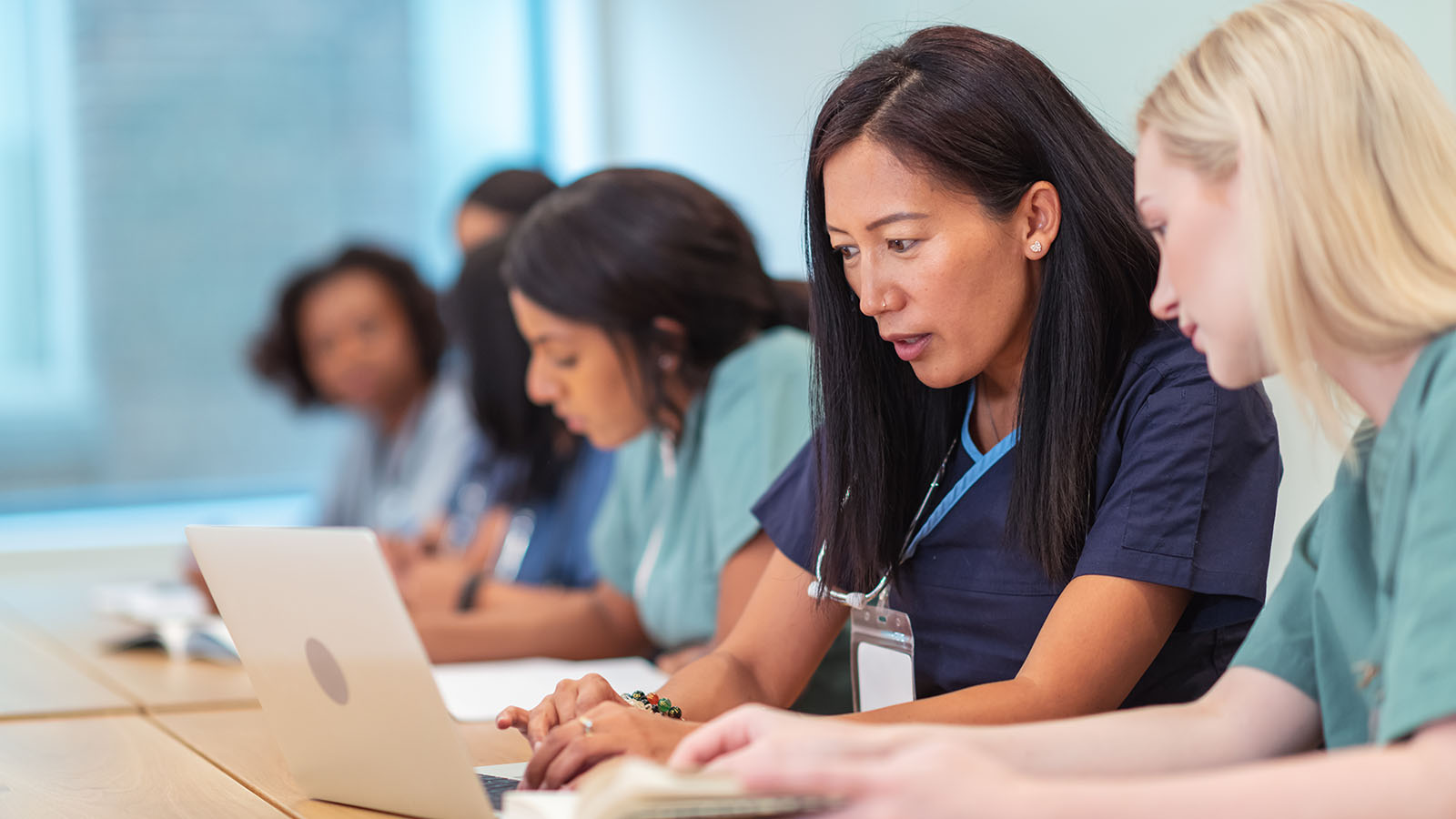 Women nurses working in a classroom on laptops.