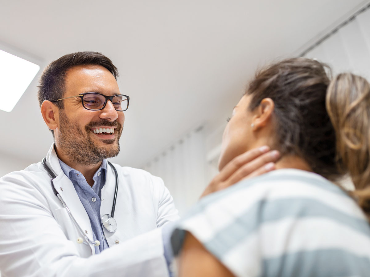 Adult male doctor examines the neck of a female patient