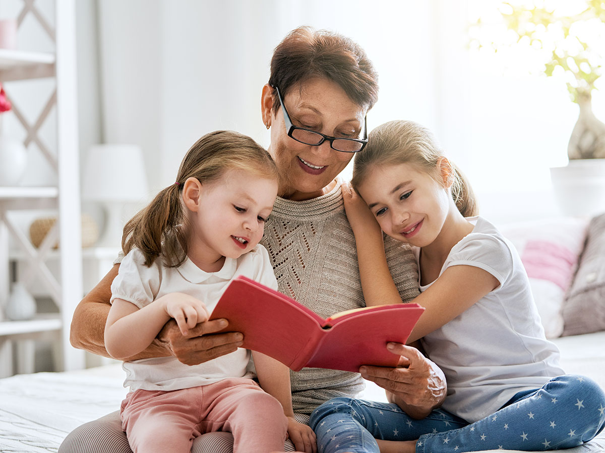 Grandmother reading a book to grandchildren
