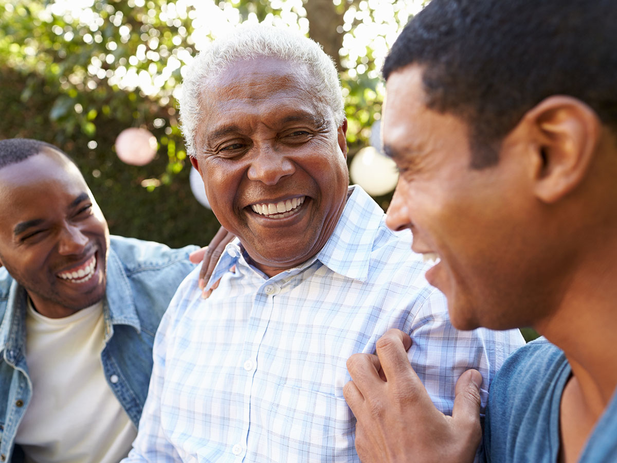 Three adult males wearing blue shirts laughing 