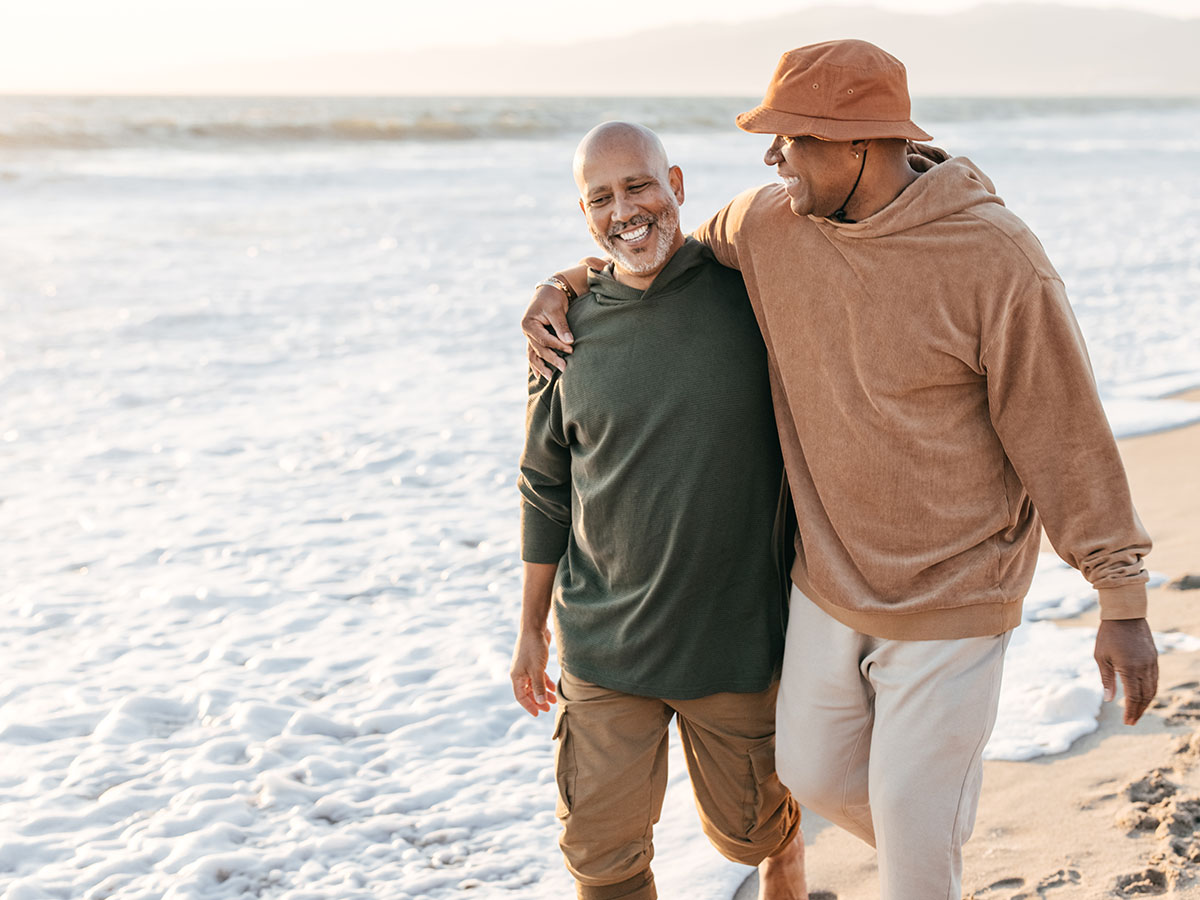 Senior adult couple walking on beach.