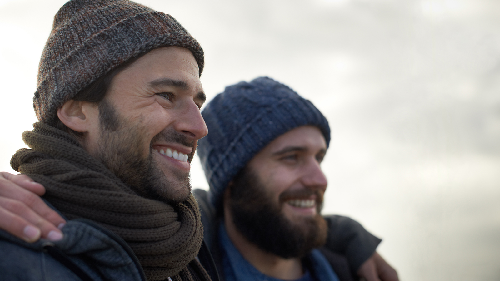 Two adult males wearing hats looking into the distance