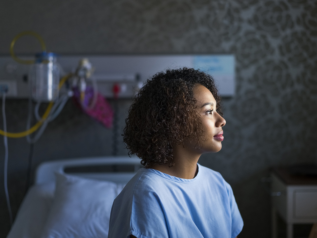 Adult woman in hospital gown looks out the window