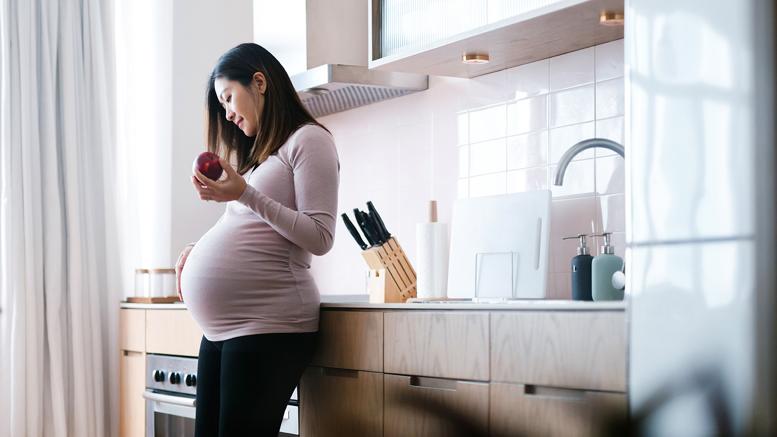 Pregnant woman standing by kitchen